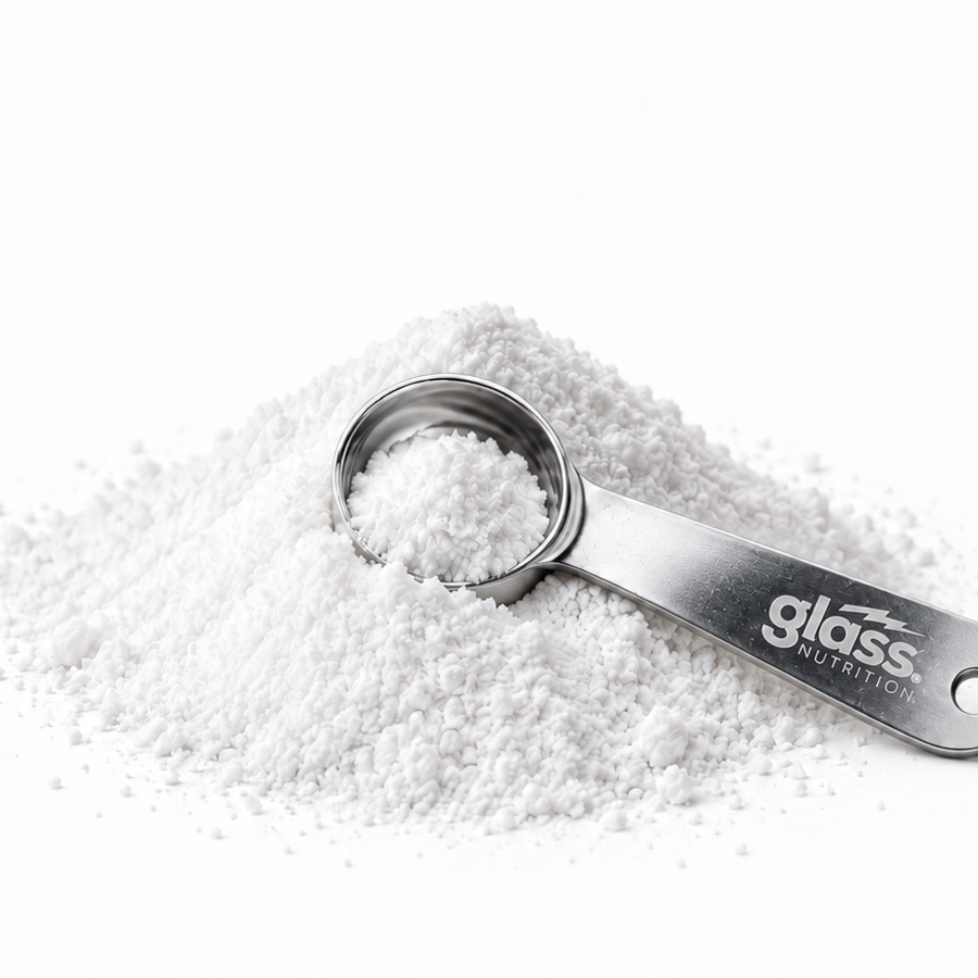 A Glass Nutrition steel scoop resting in a pile of white creatine powder