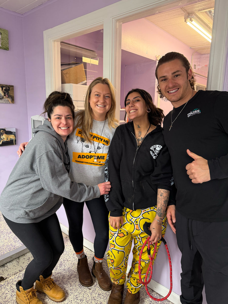 Four people posing together in a lavender shelter lobby, one holding a red leash.