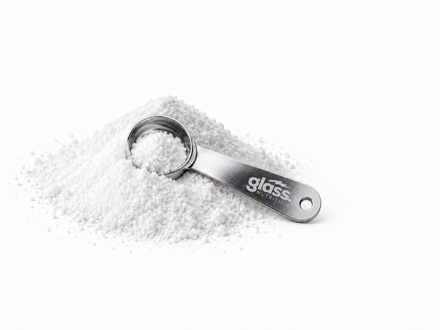 A Glass Nutrition steel scoop resting in a pile of white creatine powder